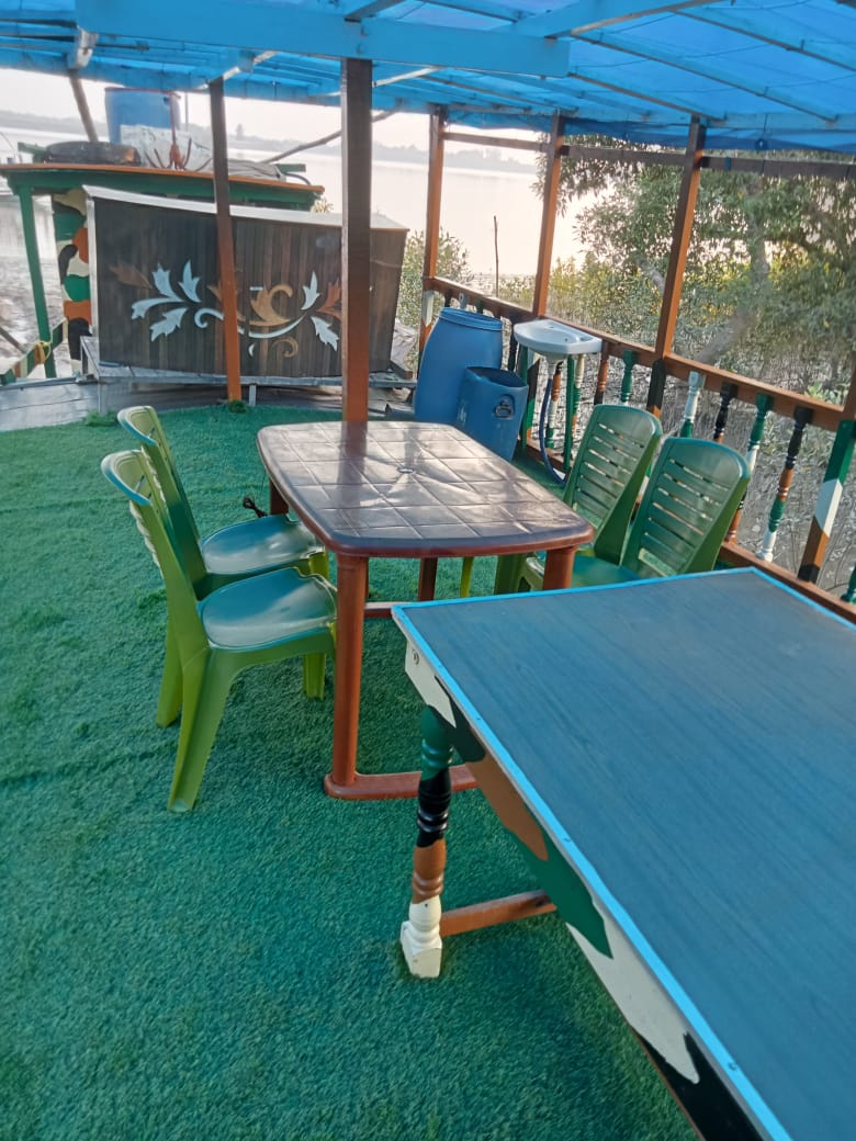 Dining table and chairs on the boat's riverside deck at dawn