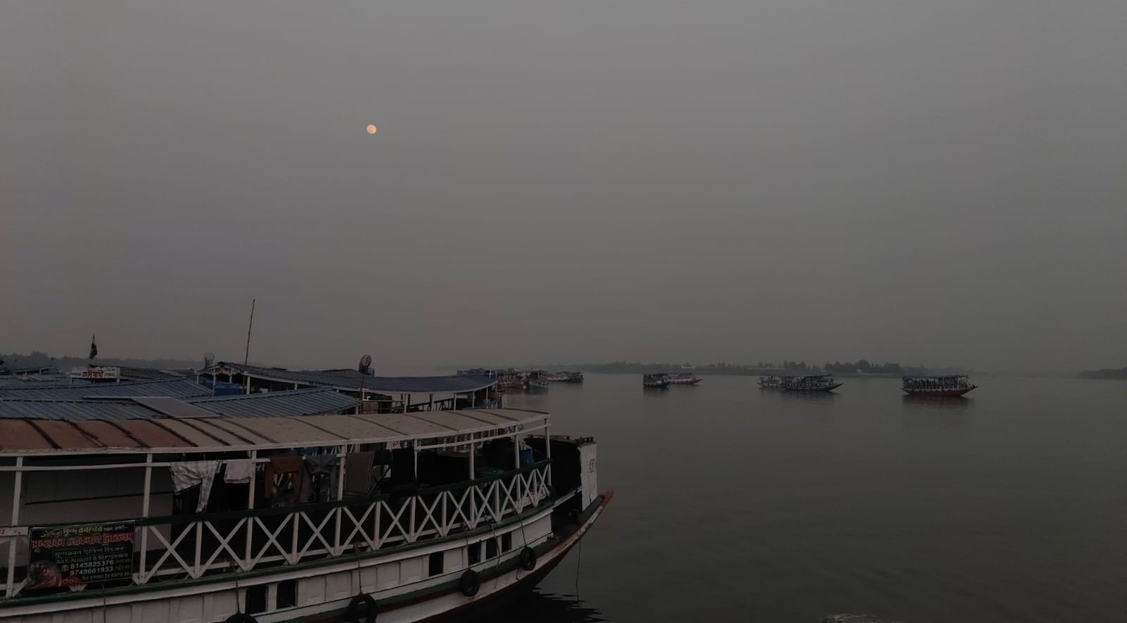 Tourist boats resting near the jetty at dusk under a rising moon