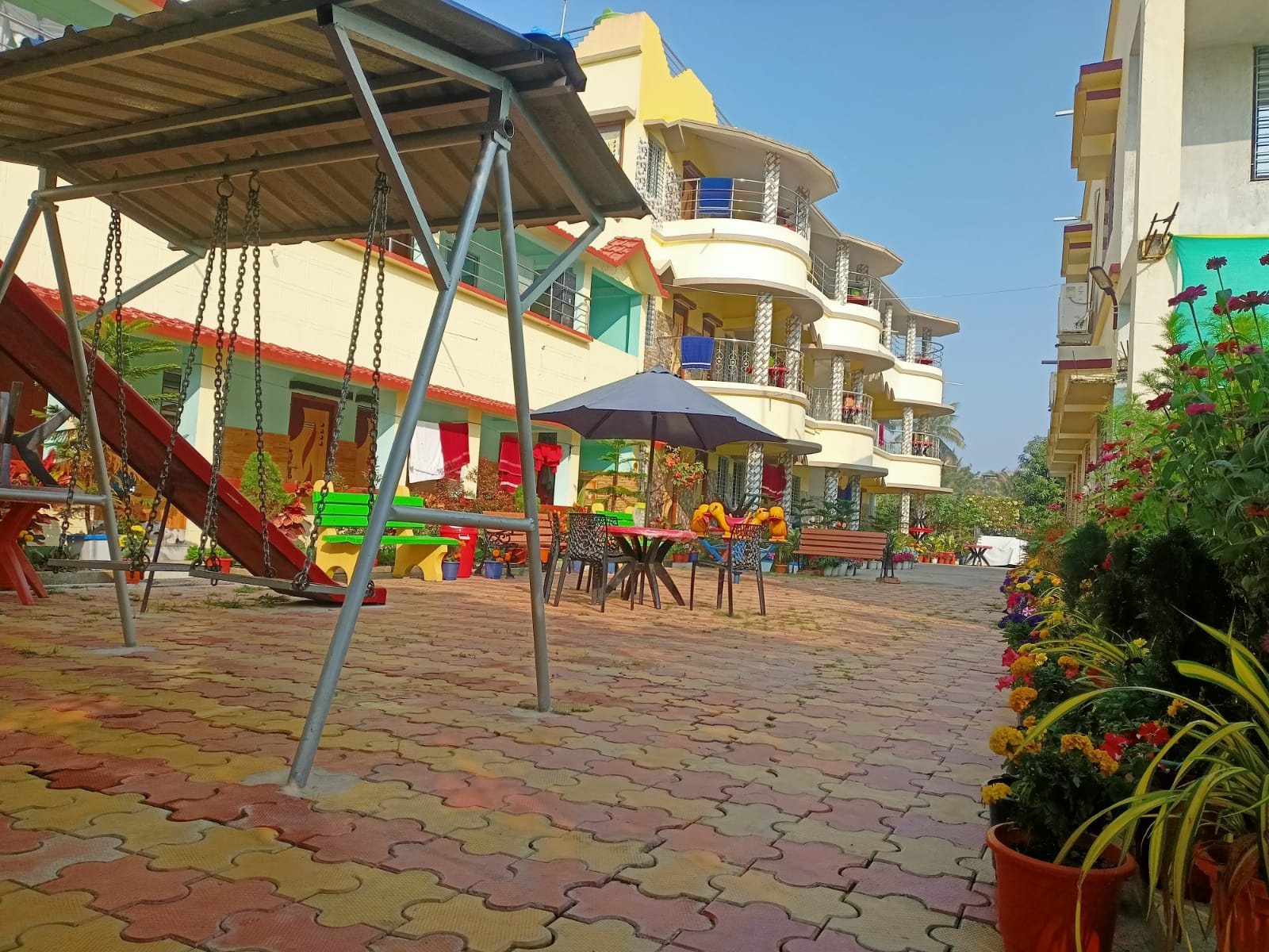 Paved courtyard with garden swing, seating and umbrellas